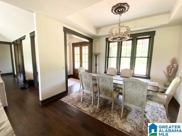 dining area with a raised ceiling, a chandelier, and dark hardwood / wood-style floors