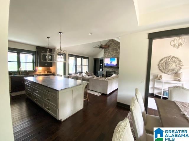 kitchen featuring a kitchen island, a healthy amount of sunlight, vaulted ceiling, and dark hardwood / wood-style flooring