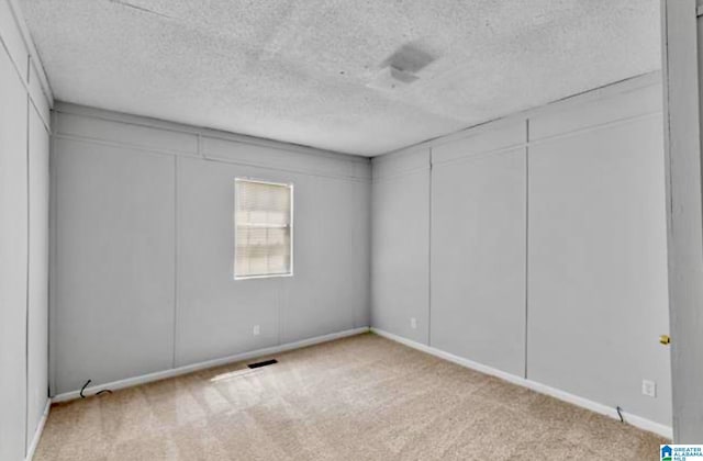 carpeted spare room with a textured ceiling