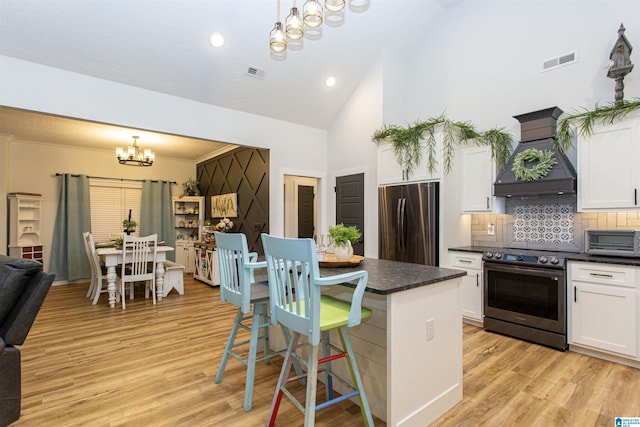 kitchen featuring decorative light fixtures, appliances with stainless steel finishes, a chandelier, and custom range hood