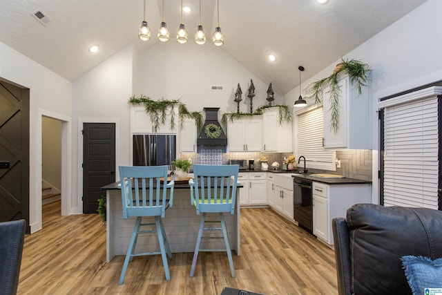 kitchen featuring decorative backsplash, premium range hood, hanging light fixtures, and a breakfast bar area