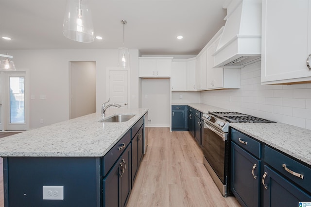 kitchen featuring a sink, blue cabinets, appliances with stainless steel finishes, and premium range hood