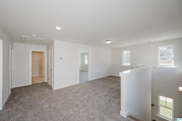 spare room with light carpet, baseboards, and attic access