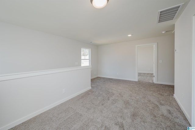 carpeted spare room featuring baseboards, visible vents, and recessed lighting