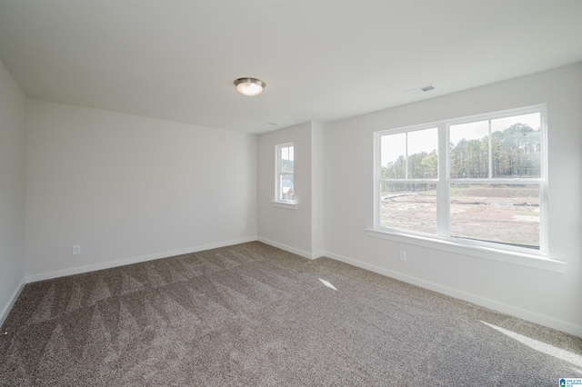 carpeted empty room featuring baseboards and visible vents