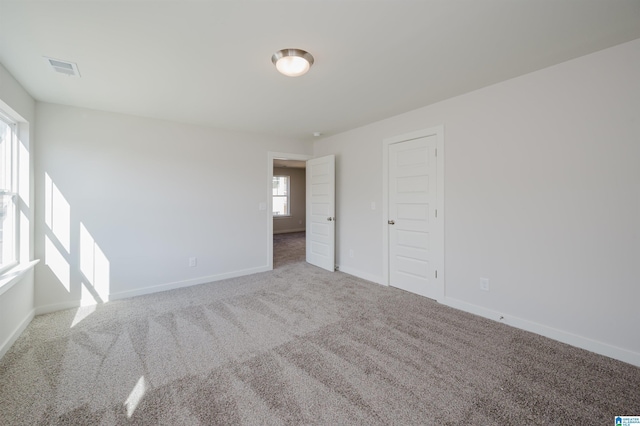 empty room featuring carpet, baseboards, and visible vents