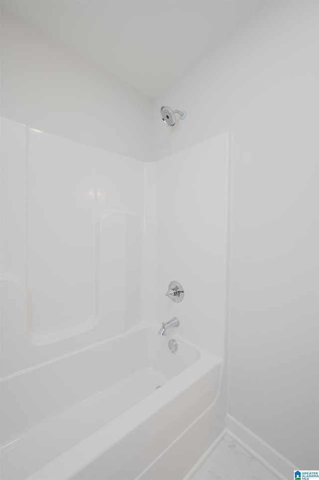 bathroom with marble finish floor,  shower combination, and baseboards