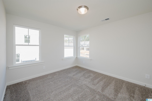 carpeted spare room featuring baseboards and visible vents