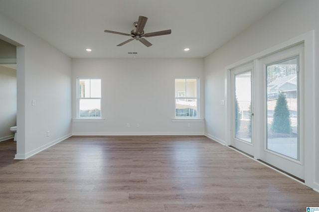 empty room featuring a wealth of natural light, wood finished floors, and recessed lighting