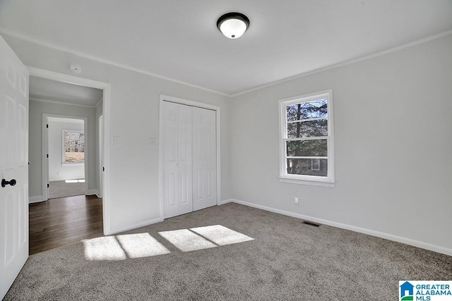 unfurnished bedroom featuring a closet, crown molding, dark carpet, and multiple windows