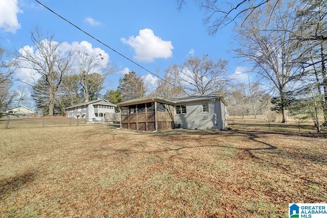 back of house with a rural view, a lawn, and a sunroom