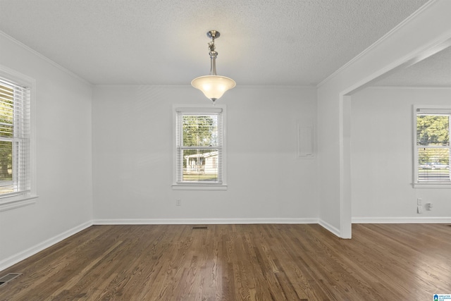 spare room with ornamental molding, a healthy amount of sunlight, and dark wood-type flooring