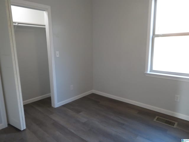 unfurnished bedroom with dark wood-type flooring and a closet