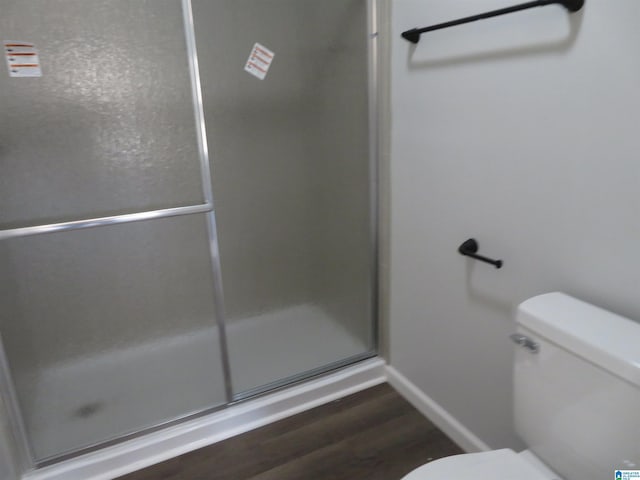 bathroom with toilet, a shower with door, and hardwood / wood-style flooring