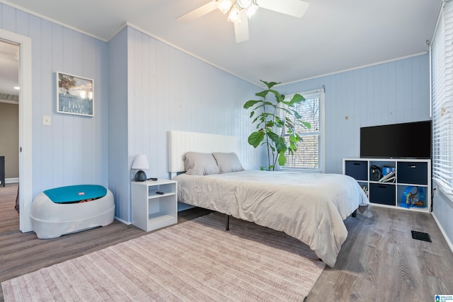 bedroom with ceiling fan, crown molding, and hardwood / wood-style floors