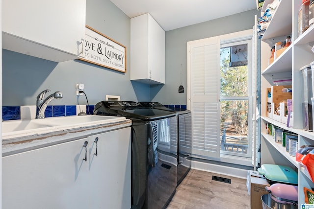 laundry room featuring light hardwood / wood-style flooring, sink, washing machine and clothes dryer, and cabinets