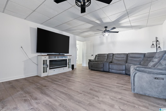 unfurnished living room with ceiling fan, a drop ceiling, and light hardwood / wood-style flooring