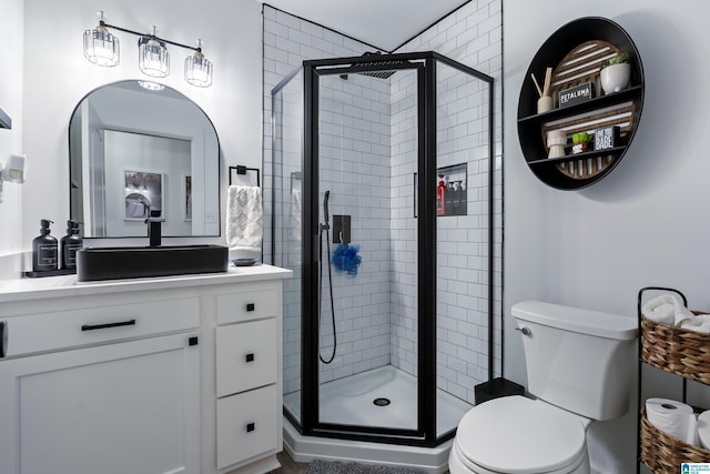 bathroom with toilet, an enclosed shower, and vanity