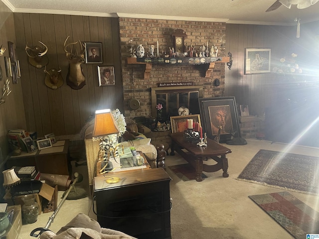 carpeted living room with a brick fireplace, wood walls, ceiling fan, and crown molding