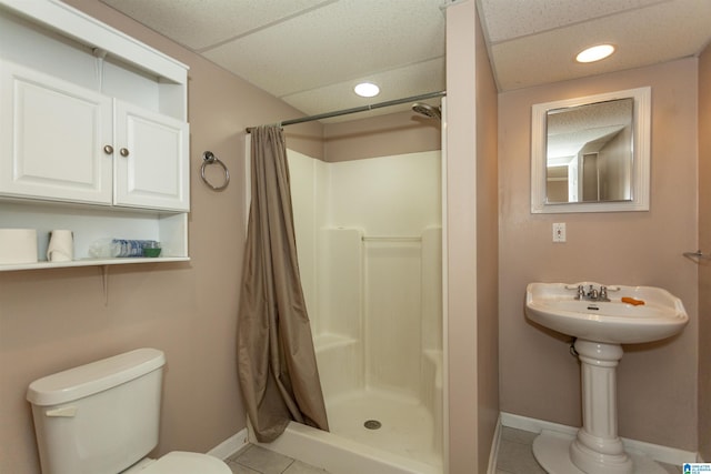 bathroom with toilet, a shower with curtain, tile patterned floors, and a drop ceiling