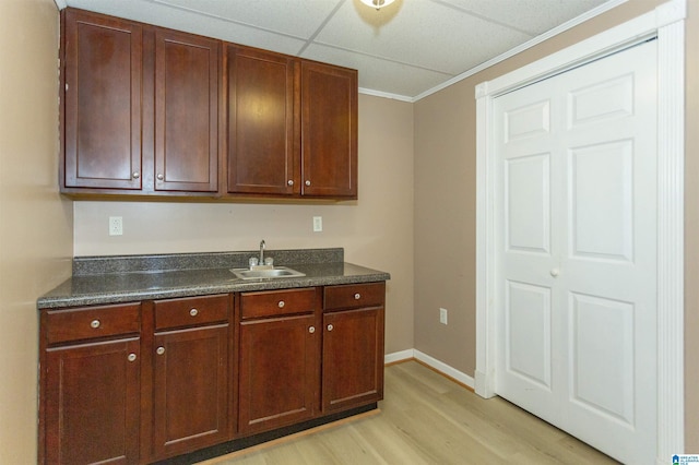 kitchen featuring light wood-type flooring, a paneled ceiling, ornamental molding, and sink