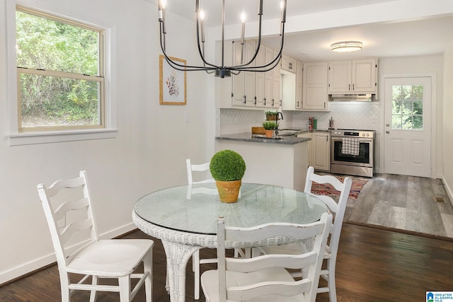 kitchen with hanging light fixtures, a wealth of natural light, stainless steel range with electric stovetop, white cabinets, and backsplash