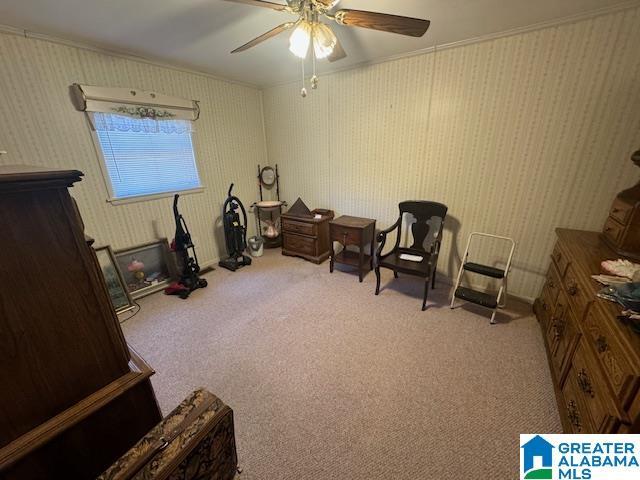 sitting room featuring ceiling fan, crown molding, and light carpet