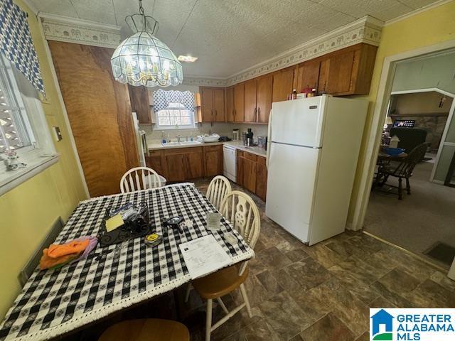 kitchen with sink, white appliances, ornamental molding, pendant lighting, and a notable chandelier