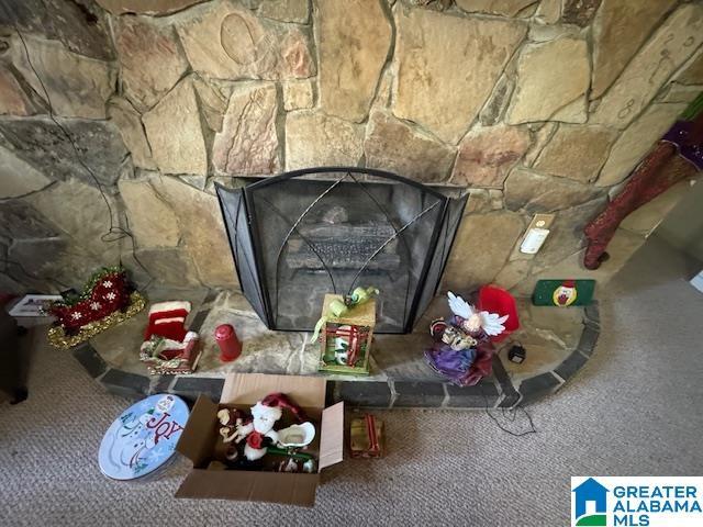 interior details featuring carpet floors and a stone fireplace