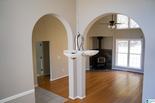 unfurnished living room with ceiling fan, tile patterned floors, and a wood stove