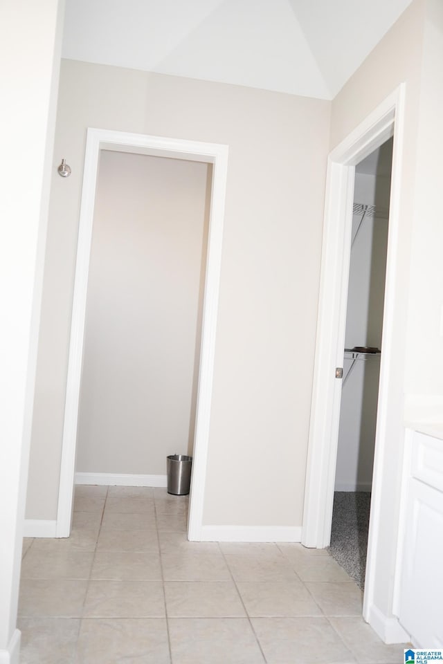 hallway with vaulted ceiling and light tile patterned flooring