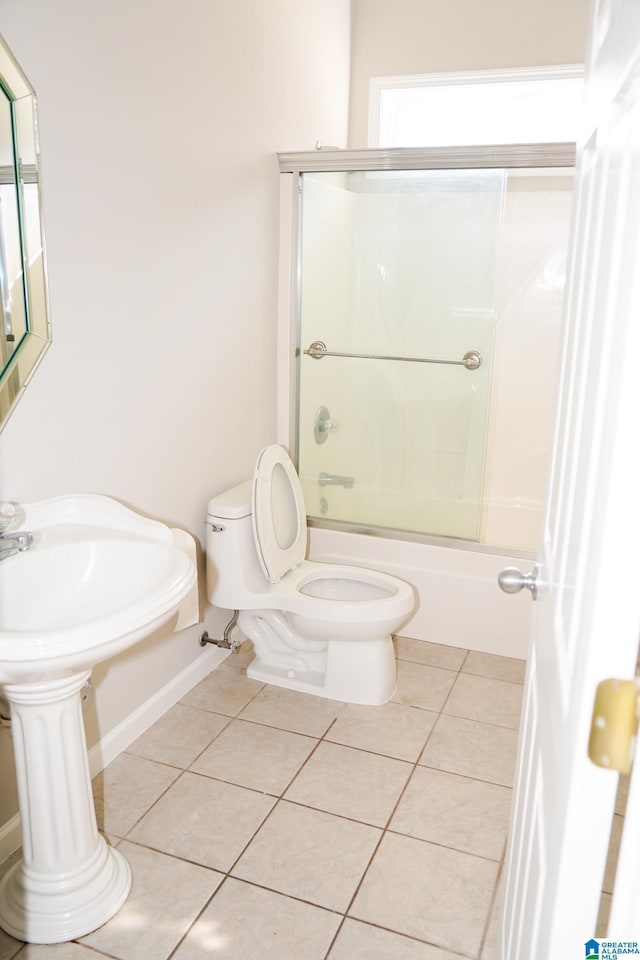 bathroom featuring tile patterned floors, toilet, and combined bath / shower with glass door