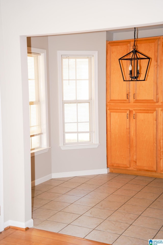 unfurnished dining area featuring light tile patterned floors and an inviting chandelier