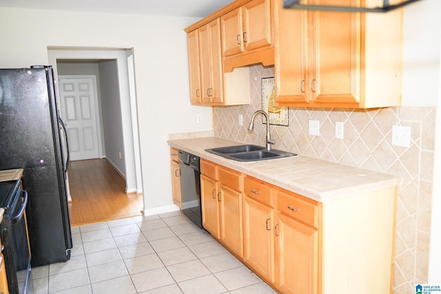 kitchen featuring tile counters, tasteful backsplash, sink, light tile patterned flooring, and black appliances