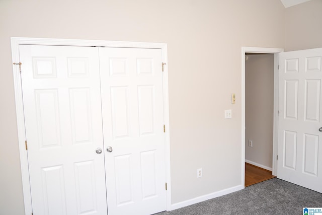 unfurnished bedroom featuring dark carpet and a closet