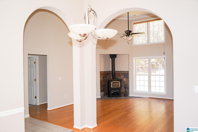 unfurnished living room with ceiling fan, light hardwood / wood-style floors, a wood stove, and ornamental molding