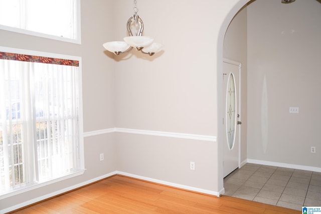 unfurnished dining area featuring an inviting chandelier, tile patterned floors, and plenty of natural light