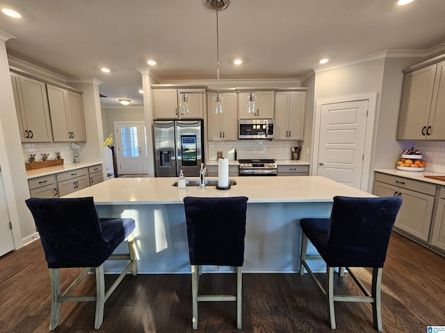 kitchen featuring stainless steel appliances, an island with sink, crown molding, and hanging light fixtures