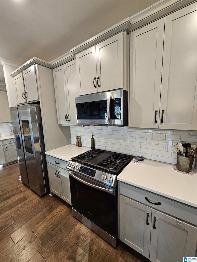 kitchen with gray cabinetry, stainless steel appliances, ornamental molding, dark hardwood / wood-style floors, and decorative backsplash