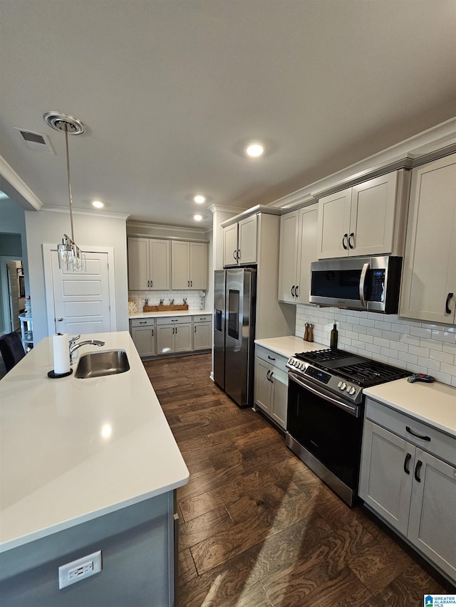 kitchen featuring gray cabinets, stainless steel appliances, an island with sink, decorative light fixtures, and tasteful backsplash