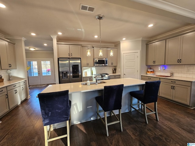 kitchen featuring a center island with sink, stainless steel appliances, a breakfast bar, pendant lighting, and sink