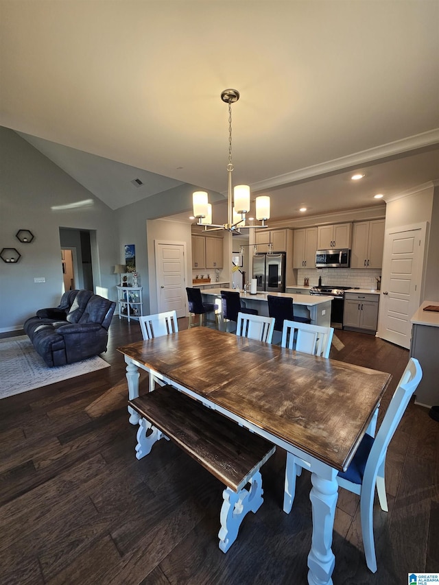 dining room with dark hardwood / wood-style flooring, an inviting chandelier, and vaulted ceiling