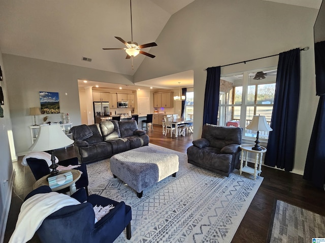 living room featuring ceiling fan with notable chandelier, high vaulted ceiling, and dark hardwood / wood-style flooring