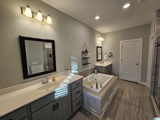 bathroom with vanity and a relaxing tiled tub