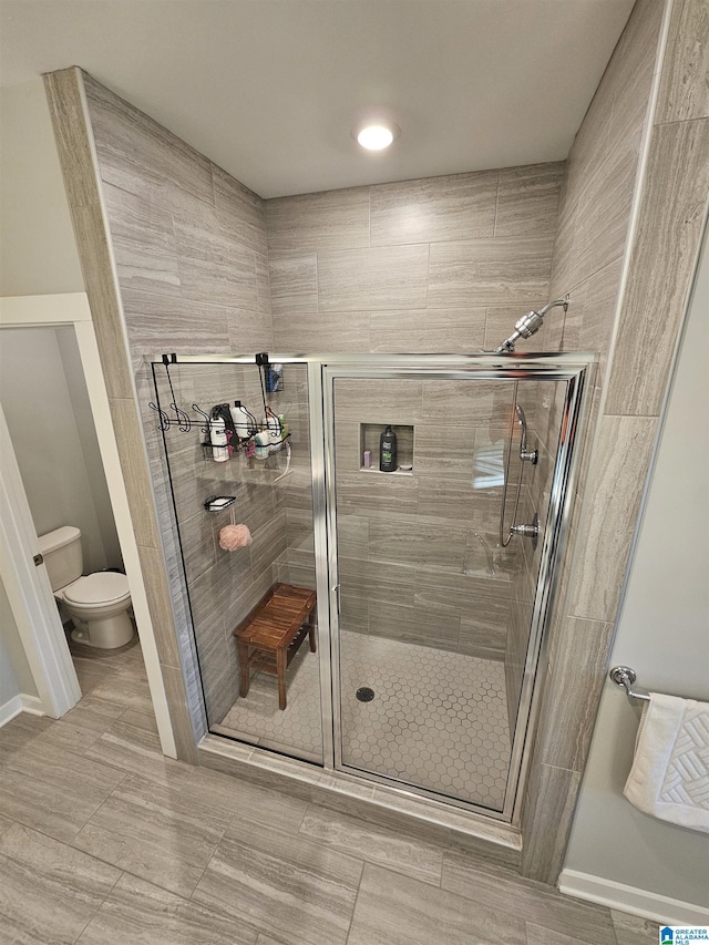 bathroom featuring toilet and a shower with door