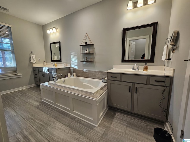 bathroom featuring tiled bath and vanity