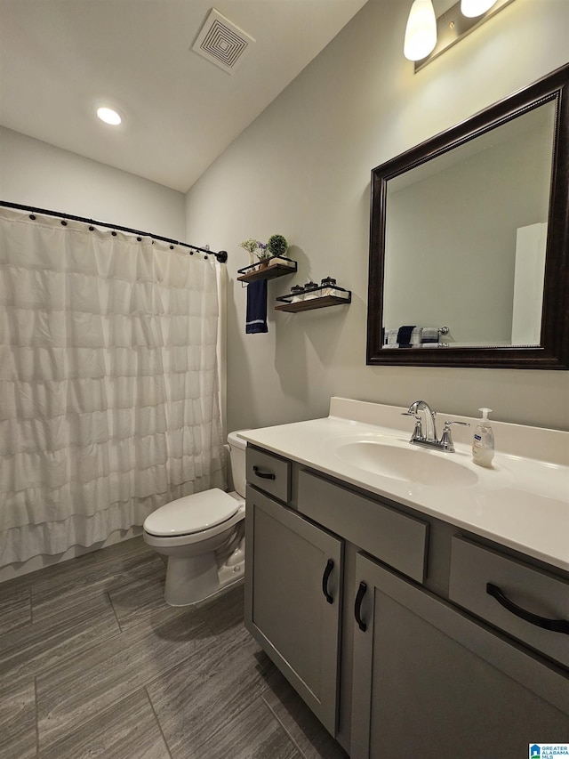 bathroom with walk in shower, vanity, and toilet