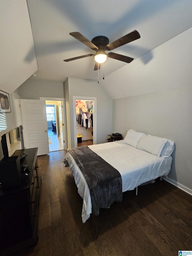 bedroom featuring a closet, ceiling fan, dark wood-type flooring, a walk in closet, and lofted ceiling