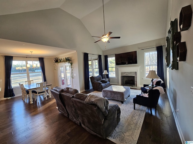 living room featuring vaulted ceiling, ceiling fan, dark hardwood / wood-style flooring, and a stone fireplace