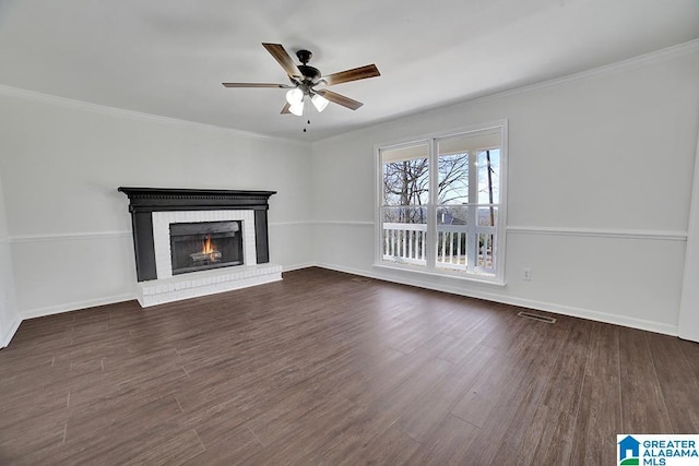 unfurnished living room with a brick fireplace, ceiling fan, dark hardwood / wood-style flooring, and ornamental molding